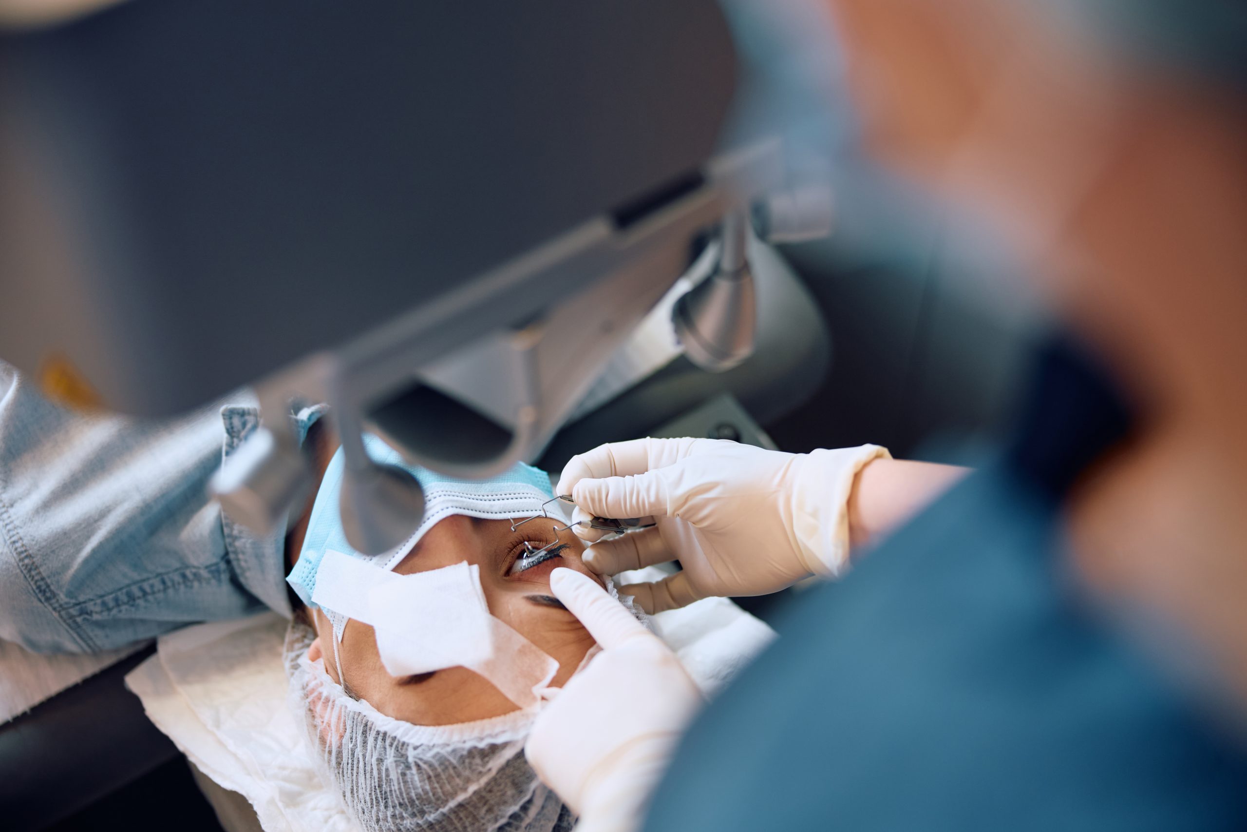 Close up of ophthalmologist preparing female patient for laser surgery at eye clinic.