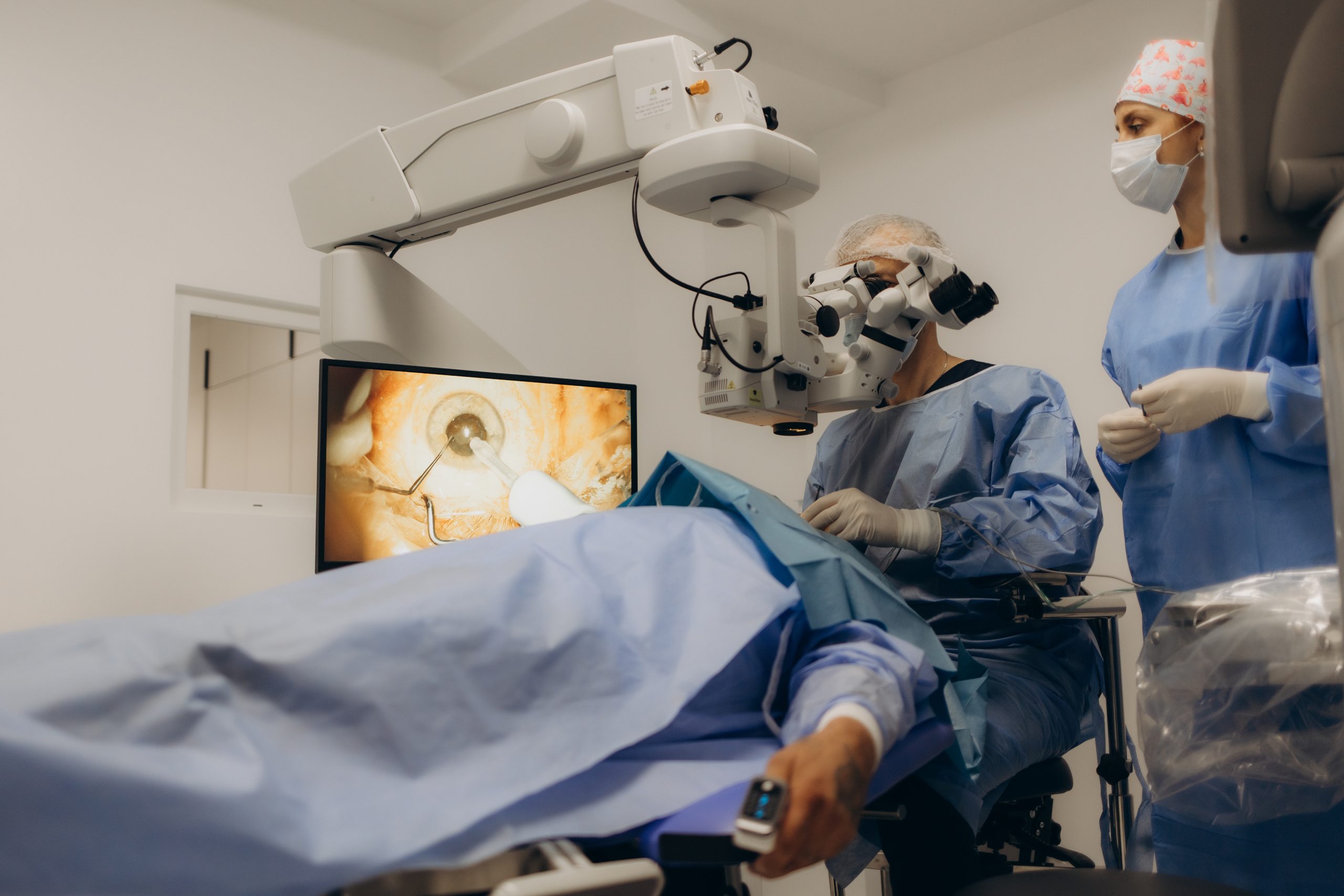 Male doctor doing surgery inside modern operating theater in surgical hospital.Microscope was use in eye surgery.Surgeon in blue sterile suit working with microscope with light effect.Medical concept.